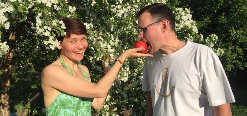 Мужчина кусает яблоко из рук женщины
