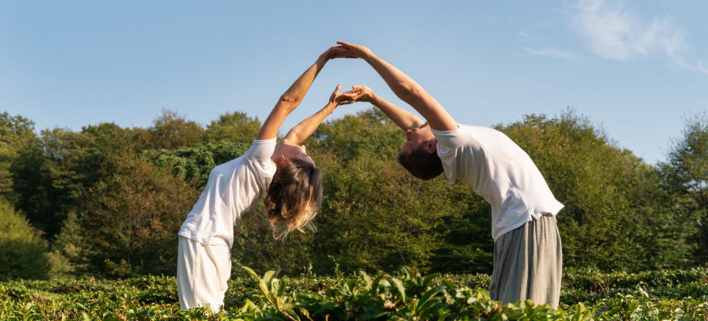 Мужчина и женщина держатся за руки в позе йоги