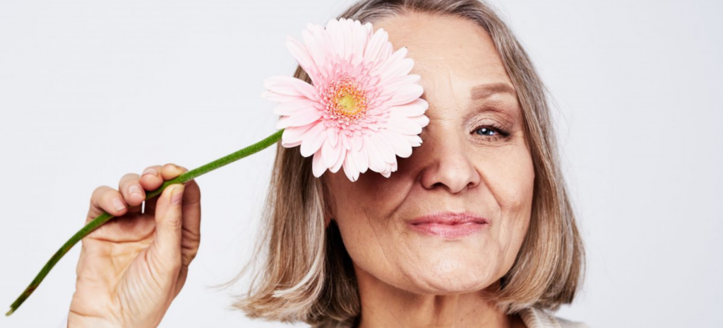 Зрелая женщина закрывает глаз цветком